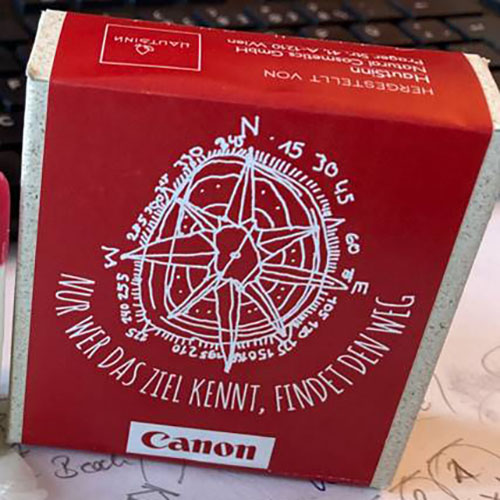 Canon Seife - Verpackung mit VOI fesch Design von Künstler David Cheng, die Verpackung ist mit dem VOI fesch Design zu sehen, ein rotes Etikett mit dem Werk darüber in weiß