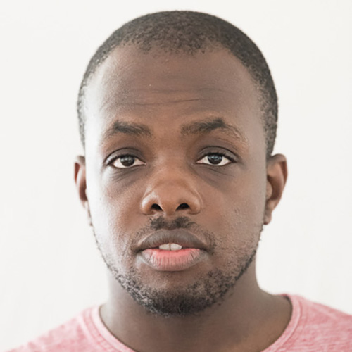 Davis Ndombasi, VOI fesch Künstler; er hat ganz kurze, wenige Millimeter kurze, dunkle Haare, seine Hautfarbe ist dunkel, er schaut neutral in die Kamera mit leicht geöffnetem Mund und er trägt einen Drei-Tage-Bart