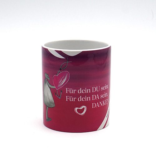 Eine Tasse in VOI fesch Design, die Farbe ist Magenta und weiß. Das Design zeigt eine Figur/einen Menschen und ein Herz mit Pfeil. Neben dem Design auf der Vorderseite "Für dein DU sein. Für dein DA sein. DANKE!".